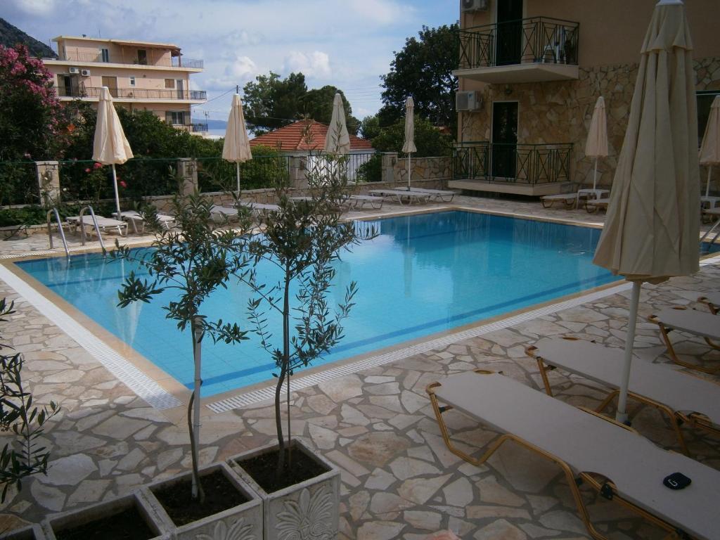 a large swimming pool with chairs and umbrellas at Petros Studios in Póros Kefalonias