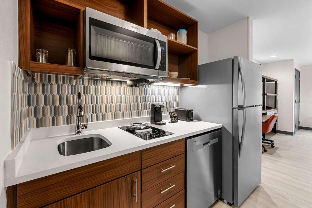a kitchen with a sink and a refrigerator at Everhome Suites Fayetteville near Fort Bragg in Fayetteville