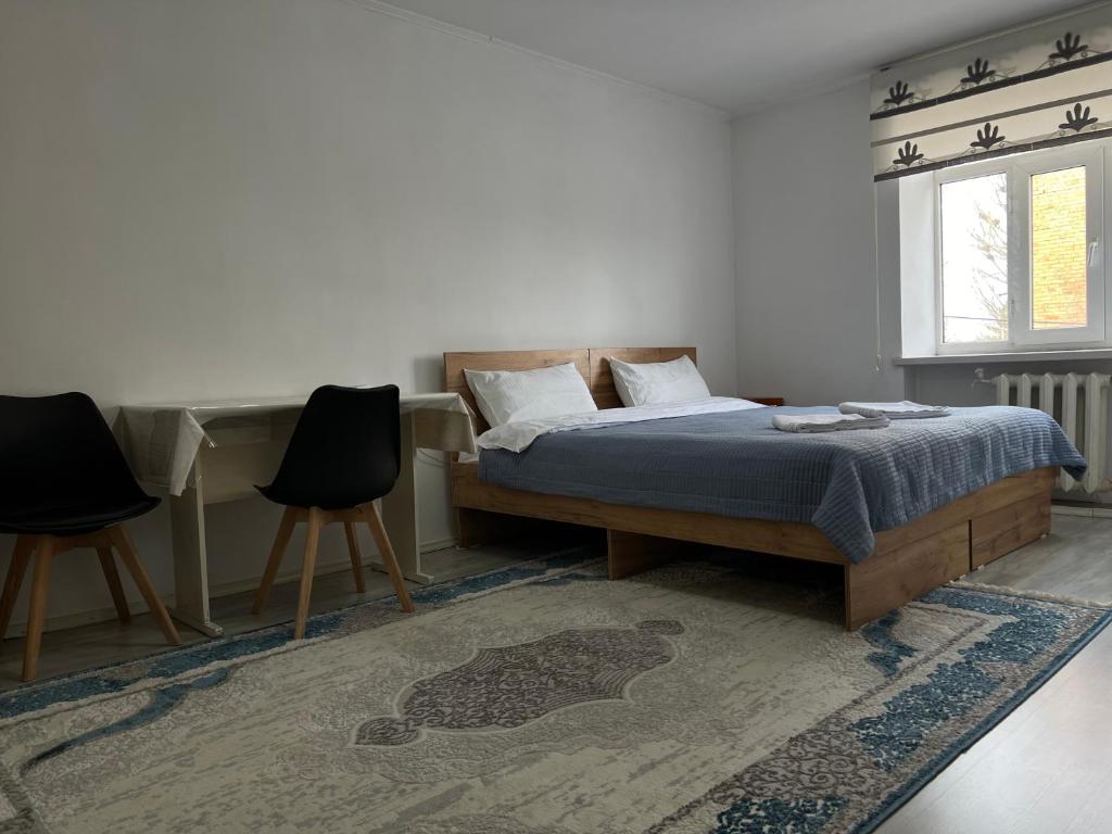1 dormitorio con 1 cama, escritorio y 2 sillas en Bayir Studio Apartment, en Karakol