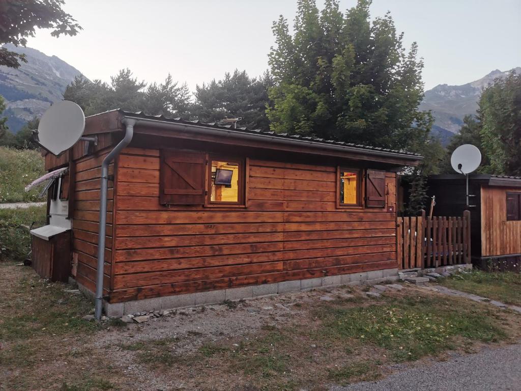une cabane en rondins avec une clôture et deux miroirs dans l'établissement Caravane 4 personnes au camping d'Aussois, à Aussois