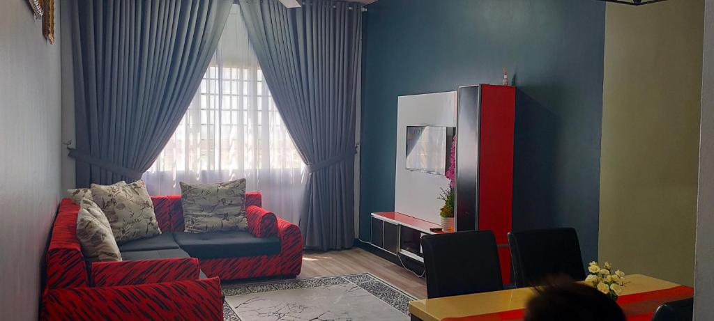 a living room with a red couch and a window at Aisy Homestay in Kuala Terengganu