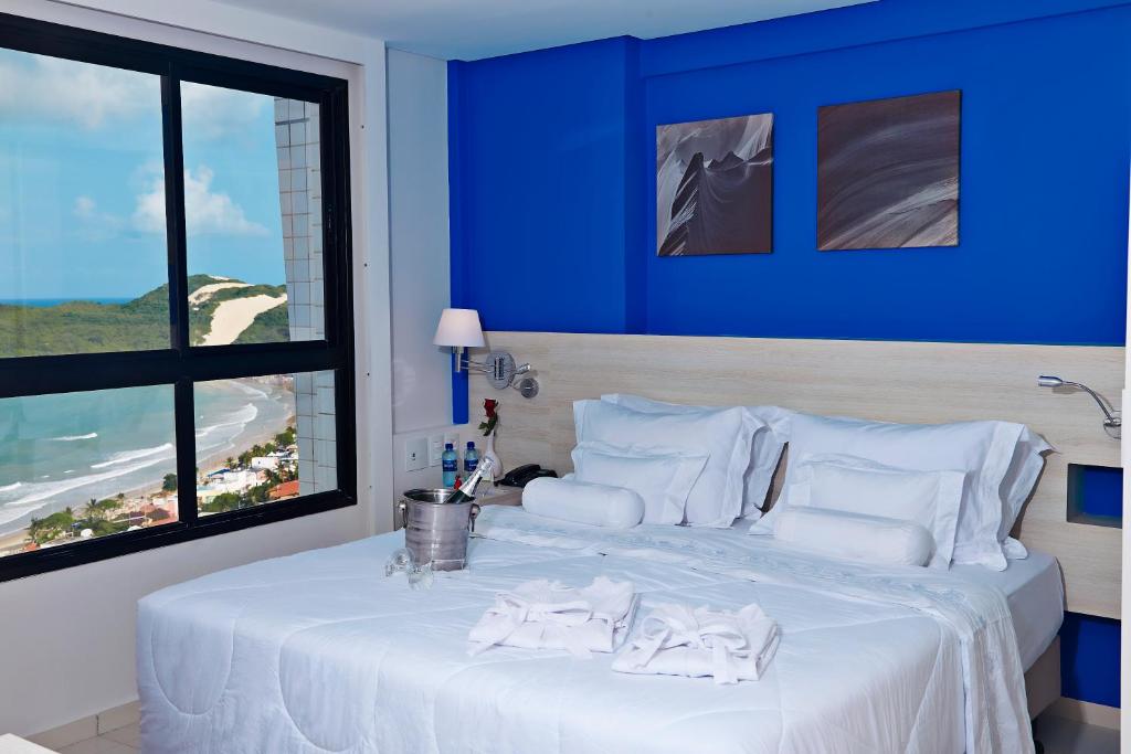 a blue bedroom with a bed with a view of the beach at Comfort Hotel & Suites Natal in Natal