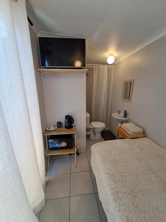 een kleine slaapkamer met een bed en een toilet bij Cozy Business overnighter in Bellville
