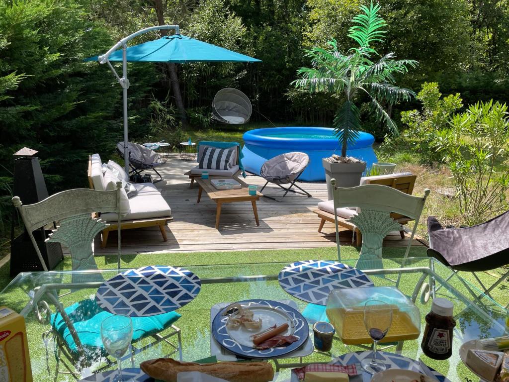 un patio avec une table, des chaises et un parasol dans l'établissement Villa du Lac,, à Biscarrosse