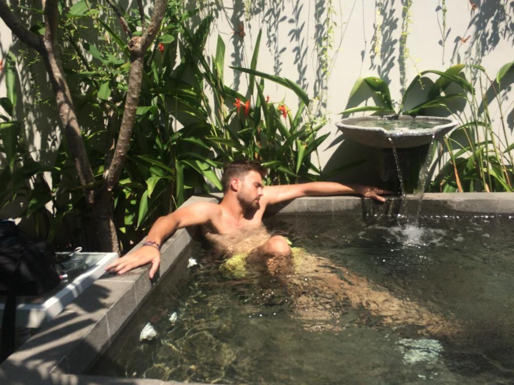 a man sitting in a bath tub with a fountain at The Patio Yogya in Yogyakarta