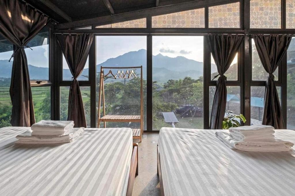 two beds in a room with a large window at Nắng Villa - Greenfield Villas in Ba Vì