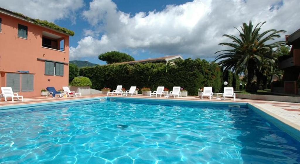 una grande piscina con sedie e un edificio di Appartamenti Maricampo by HelloElba a Marina di Campo