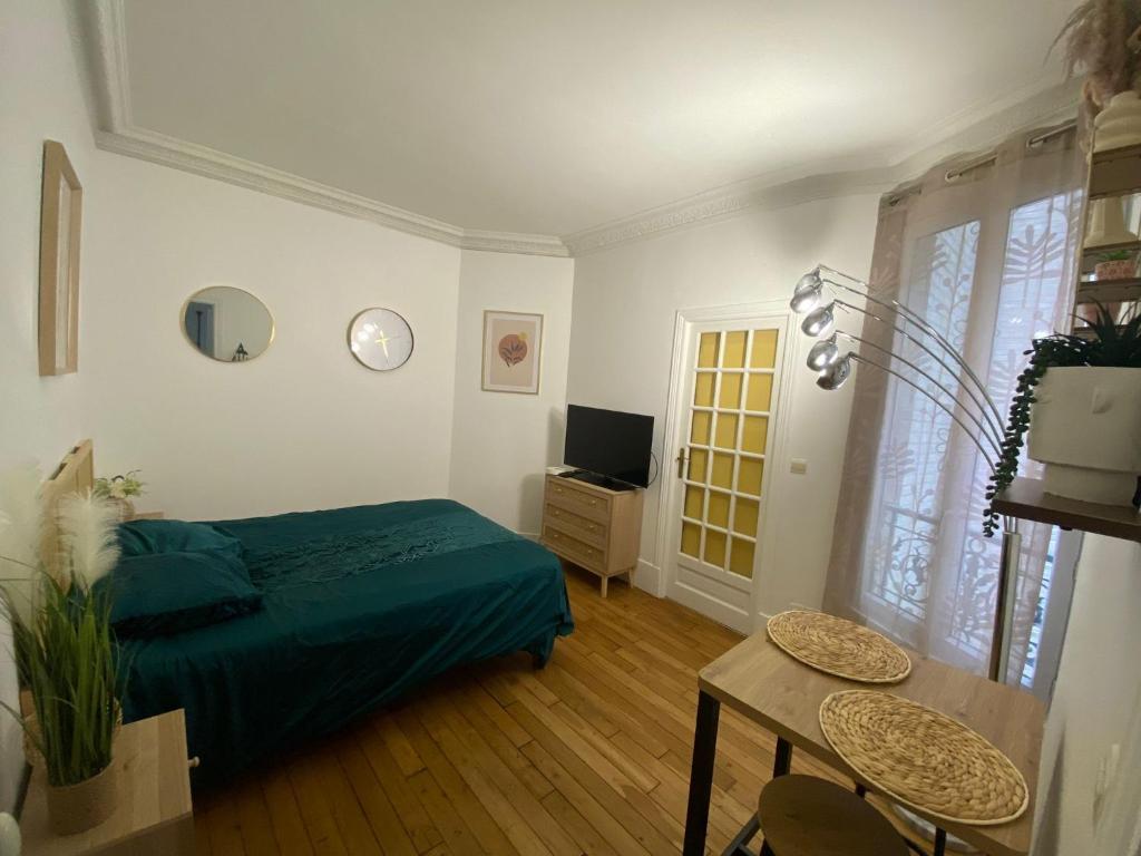une chambre avec un lit, une table et une télévision dans l'établissement L'étoile de duhesme, à Paris