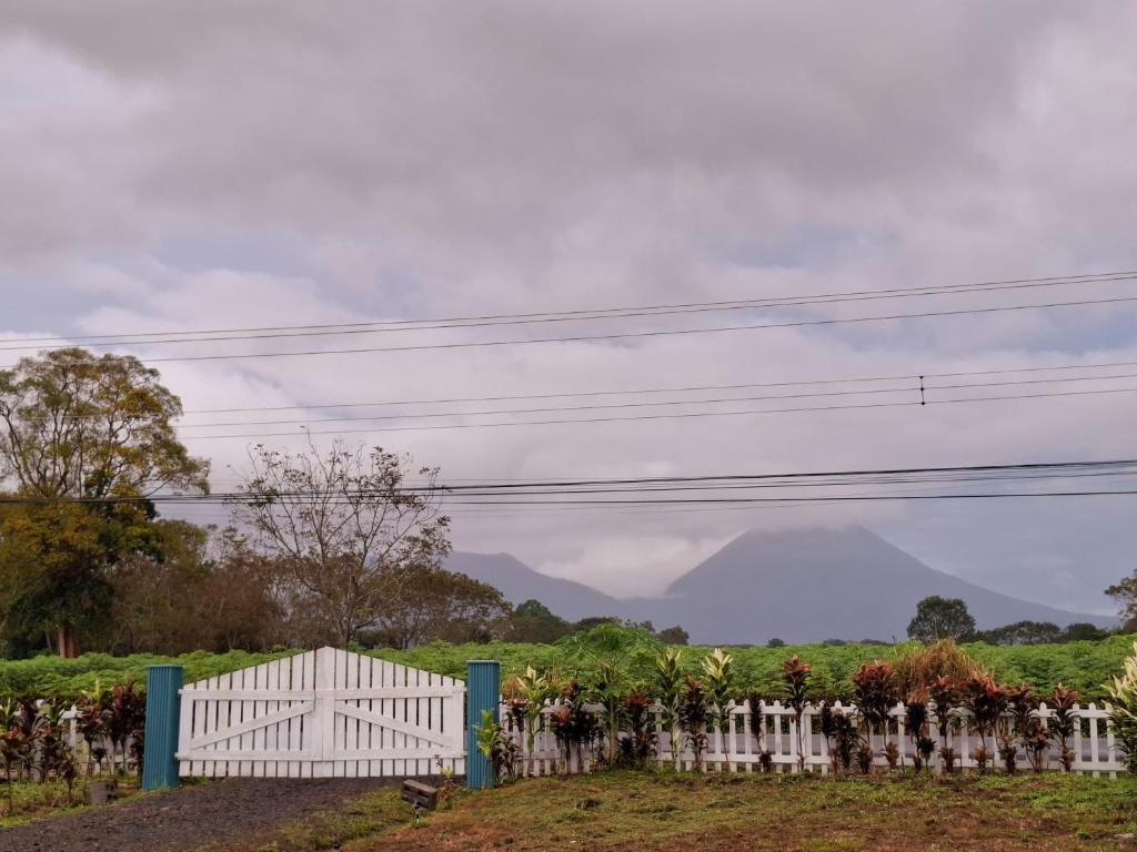 a white fence in a field with mountains in the background at Yin Garden Lodge Fortuna in Fortuna