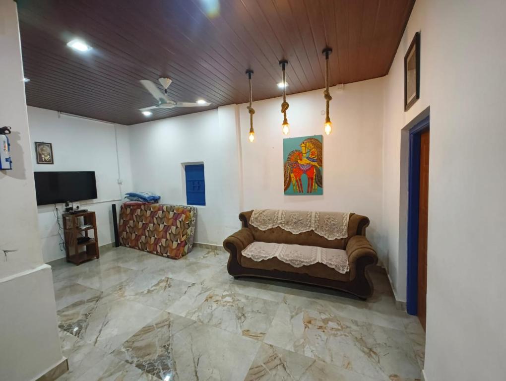 a living room with a couch and a tv at Blue Bell Homestay in Udupi