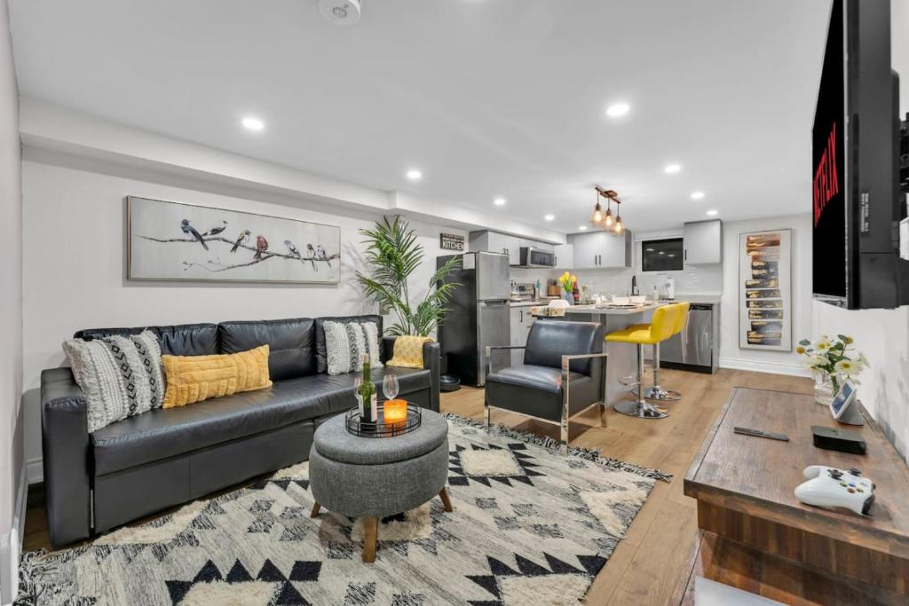 een woonkamer met een bank en een keuken bij 2 BR ground-level suite in a bungalow with full kitchen, parking, and 20 mins to Downtown in Toronto