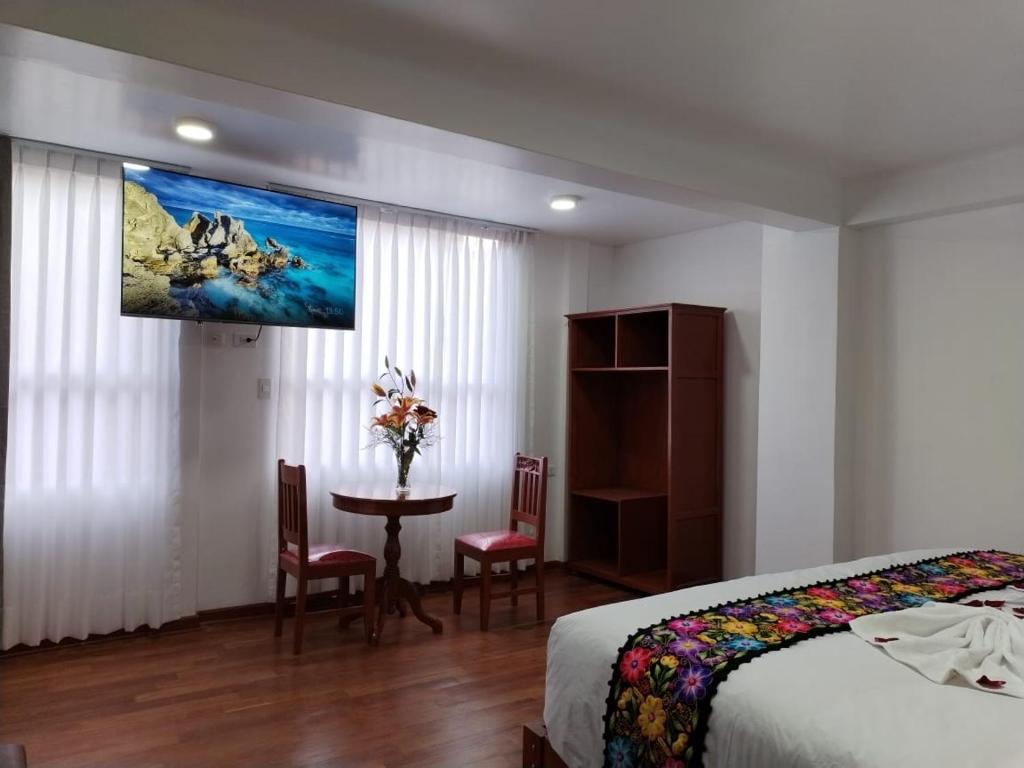 库斯科Kantu hotel的一间卧室配有一张床、一张桌子和一台电视。