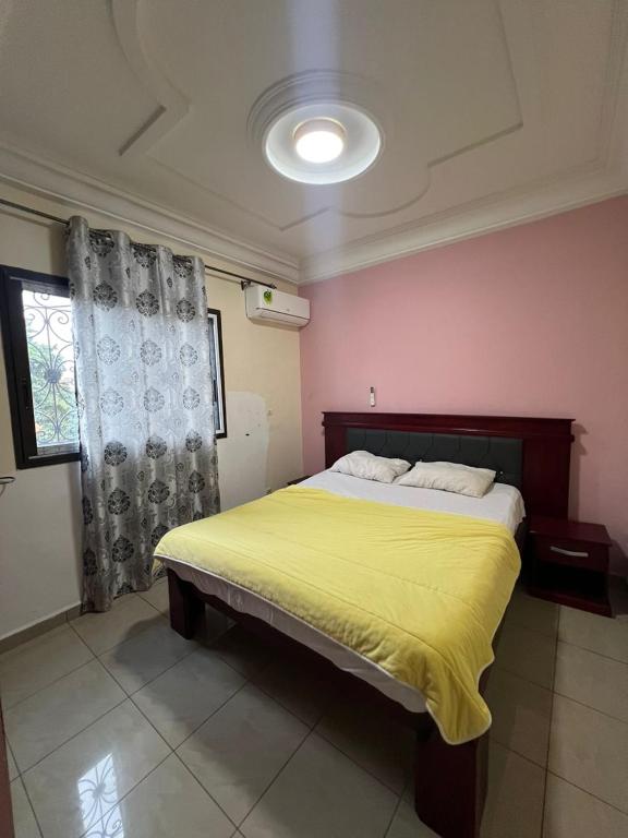 ein Schlafzimmer mit einem großen Bett und einer gelben Decke in der Unterkunft Beau séjour in Jaunde