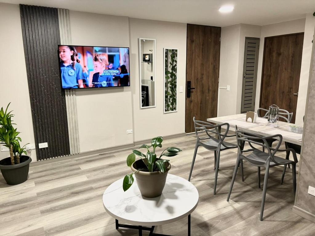a living room with a table and a tv on a wall at Apartamento 7, Parque de la 93 in Bogotá