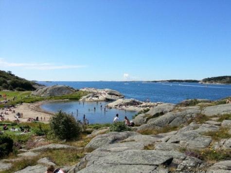 a group of people on a beach near a body of water at Mysig lägenhet med villakänsla in Gothenburg