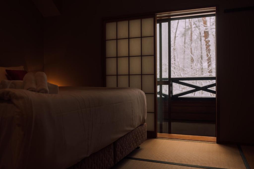 a room with a bed and a sliding glass door at Double Black Hotel in Hakuba