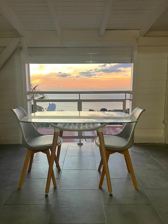 Una mesa y sillas en un balcón con vista al mar. en Tropical valley lodge 2, en Vieux-Habitants