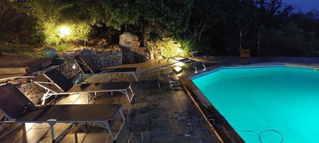 - une piscine de nuit avec des chaises et une table dans l'établissement Studio charmant avec piscine partagée à Draguignan, 42 m², à Draguignan