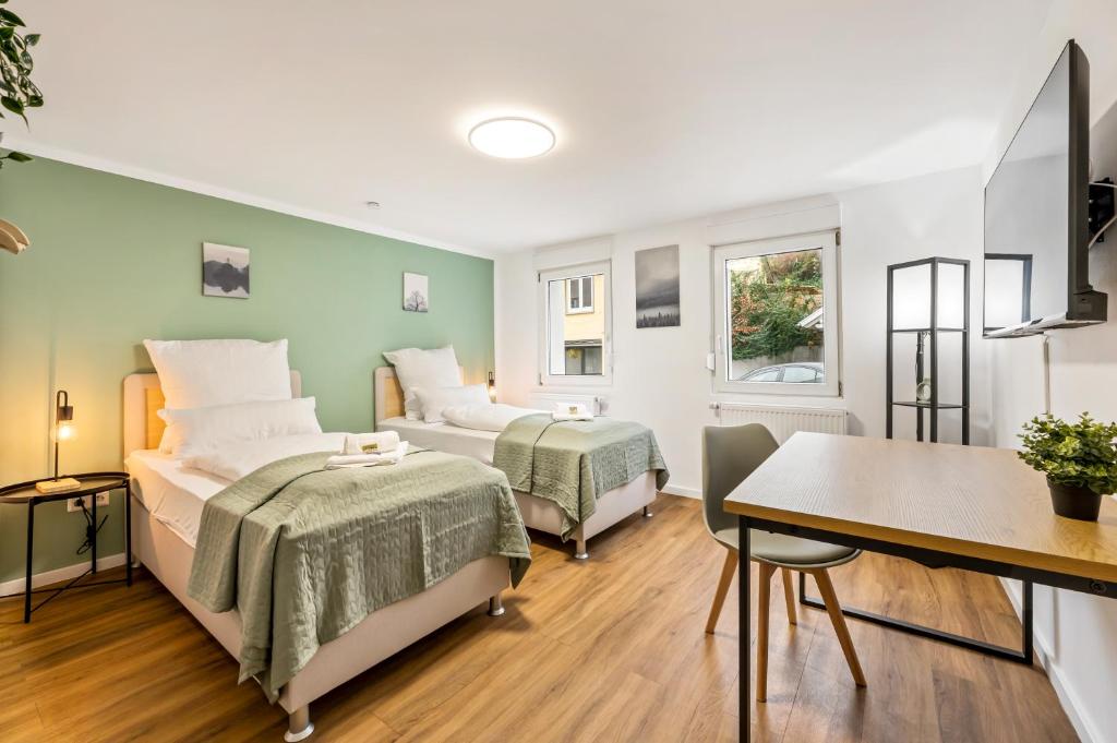 Un dormitorio con dos camas y una mesa y un escritorio. en Sali Homes Ziegeleihaus, en Heilbronn