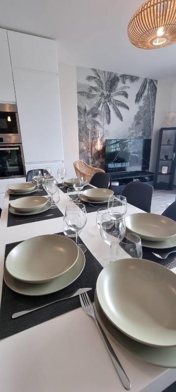 - une table avec des assiettes blanches et des verres à vin dans l'établissement Maison Cosy Coco 1h Paris et 2h plages Normandie, à Broué