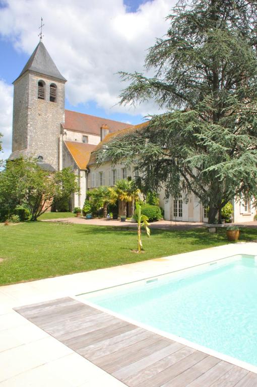 une personne debout à côté d'une piscine en face d'une église dans l'établissement Le Prieuré Saint Agnan, à Cosne Cours sur Loire