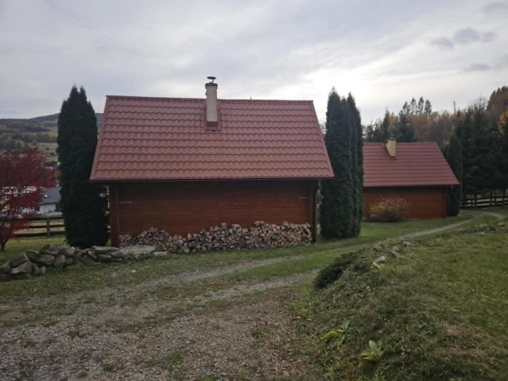 una casa con techo rojo en un campo en Domki pod Lasem Rymanów Zdrój, en Rymanów-Zdrój