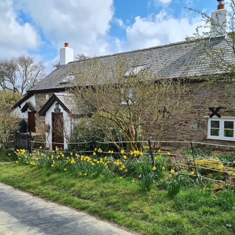 an old stone house with flowers in front of it at Character cottage with spectacular views in Church Stoke