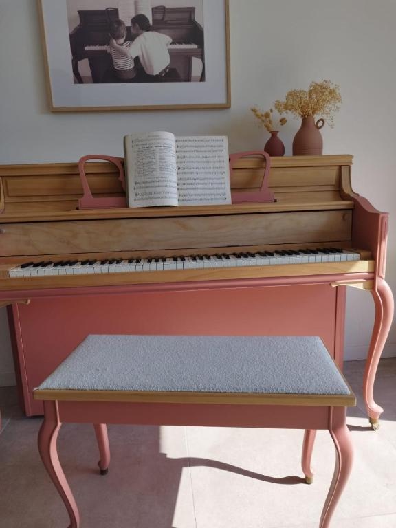 un piano en bois avec un banc devant lui dans l'établissement Cadre Verdoyant et Plage à Pied, à Le Minihic-sur-Rance