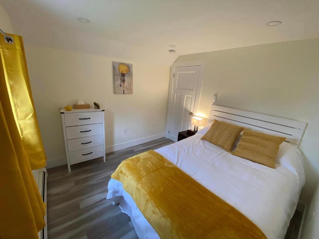 a bedroom with a large white bed and a dresser at Jeans Place A Hot tub Oasis in Lewisporte