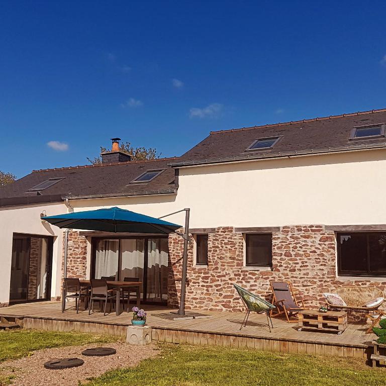 Cette maison dispose d'une terrasse avec une table et un parasol bleu. dans l'établissement La Réjardière aux portes de Brocéliande, à Iffendic