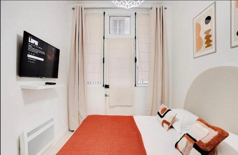 Cette petite chambre blanche dispose d'un lit et d'une télévision. dans l'établissement Charmant studio au cœur de paris, à Paris
