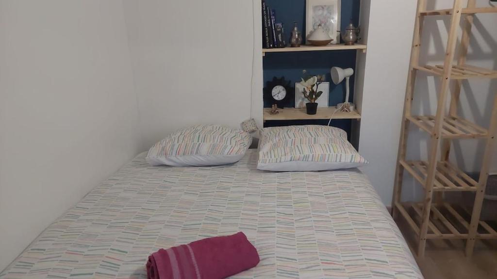 a bed with two pillows in a room at Le Nid, petit studio cosy et central in Besançon