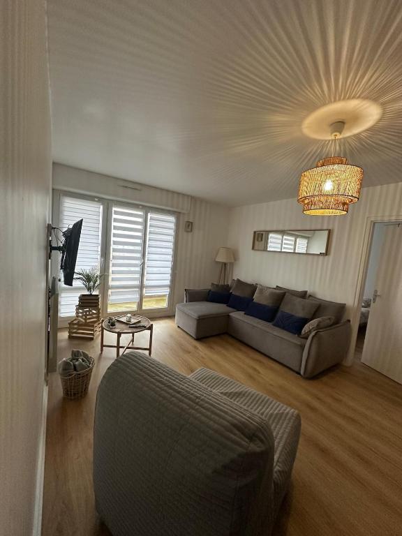 a living room with a couch and a chandelier at Au calme in Saint-Brieuc