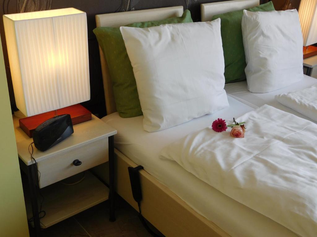 Una cama con teléfono y dos flores. en Hotel Golden Dragon, en Dessel