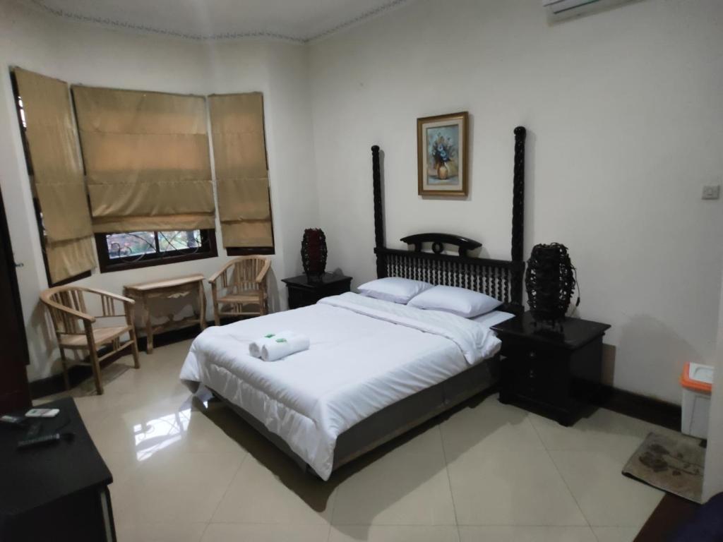 a bedroom with a large bed and chairs in it at Tirto 27 homestay in Yogyakarta