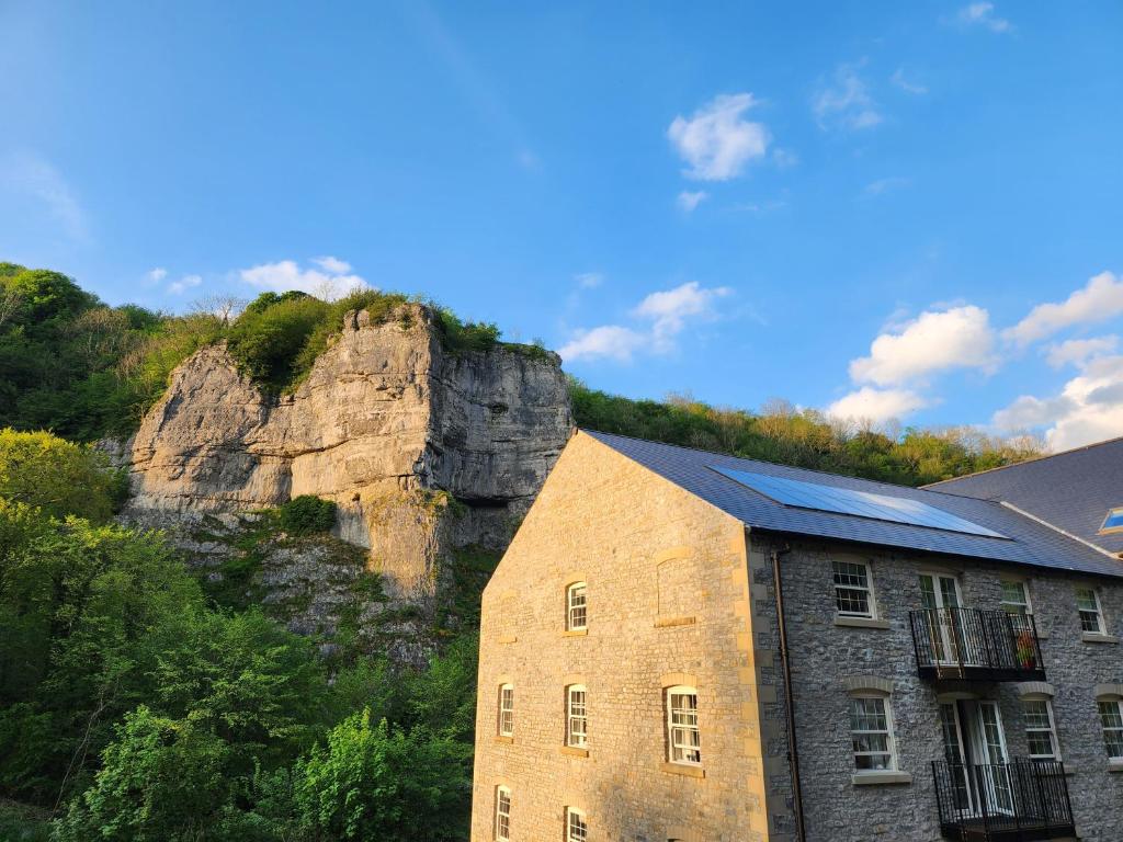 a stone building with a mountain in the background at Rock Mill Retreat in Stony Middleton