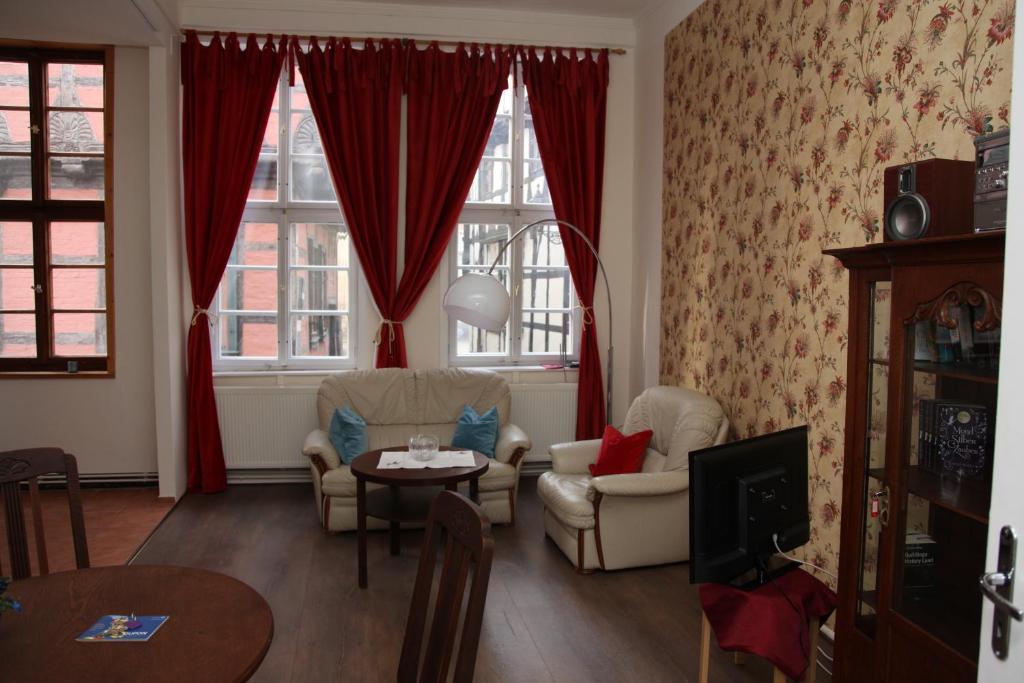 a living room with red curtains and a table and chairs at Ferienwohnung Höllenblick in Quedlinburg