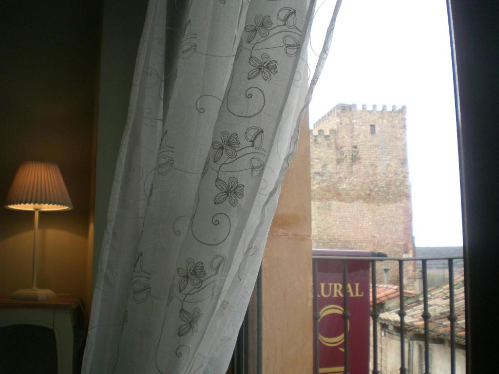 a window with a curtain with a view of a castle at Casa del Castillo in Sigüenza