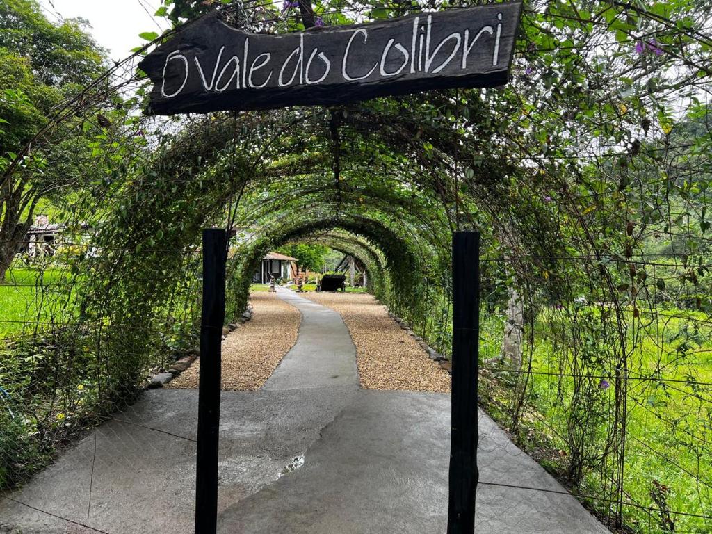 a sign for a walkway with an ivy tunnel at O Vale do Colibri in Blinha