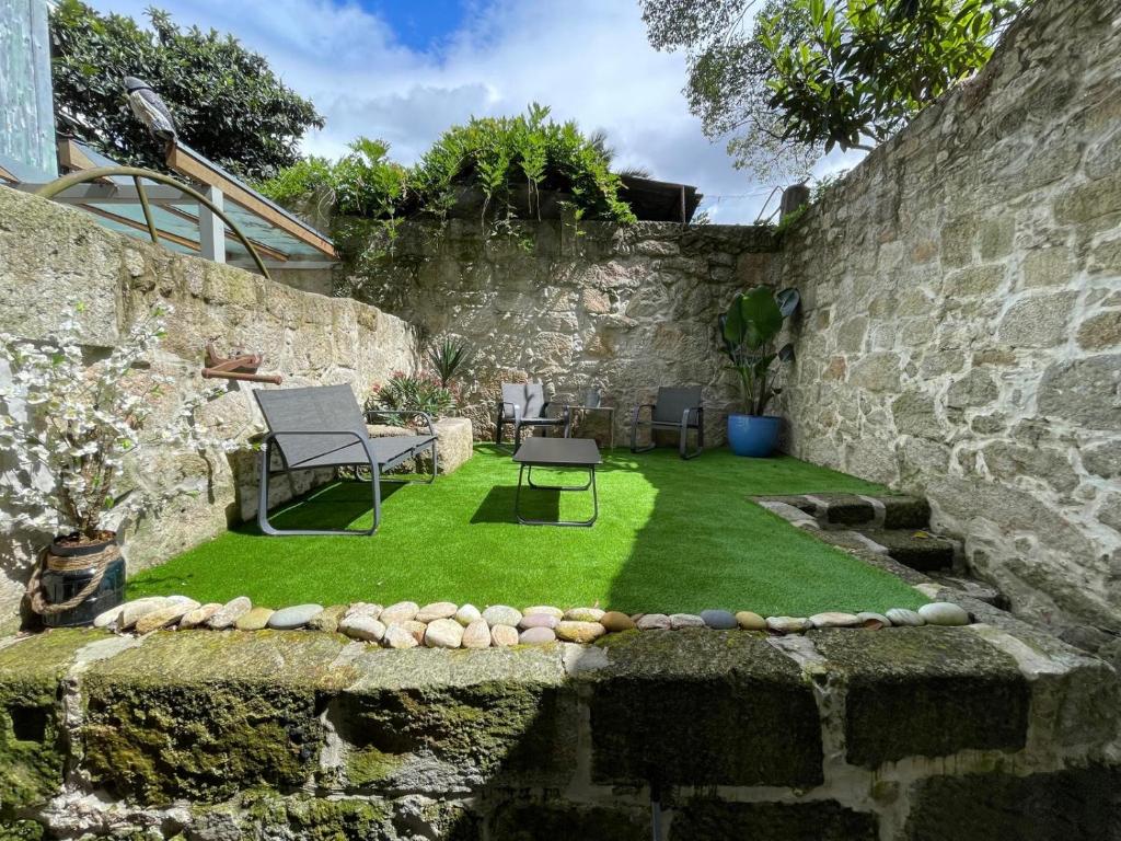 a garden with grass and a stone wall at Sol Garden in Porto