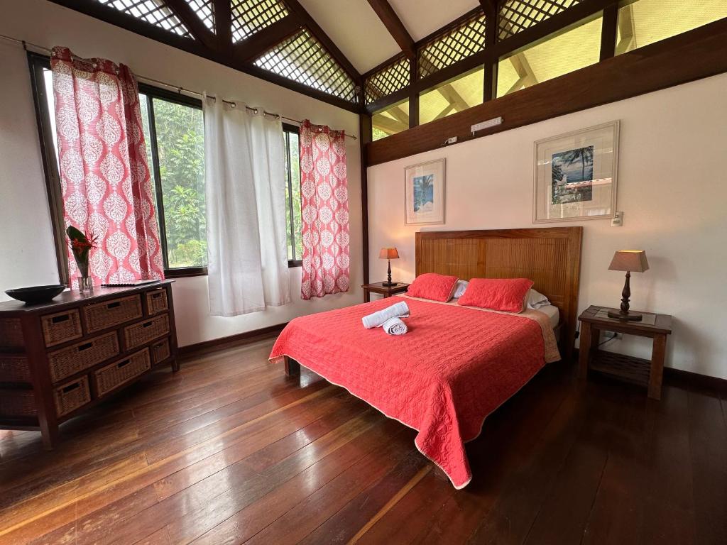 a bedroom with a bed with red sheets and windows at Hotel Kenaki Lodge in Cahuita