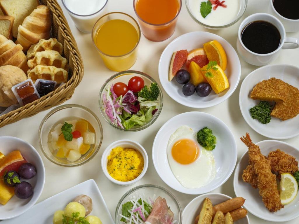 a table with plates of breakfast foods and drinks at Dormy Inn Kanazawa Natural Hot Spring in Kanazawa