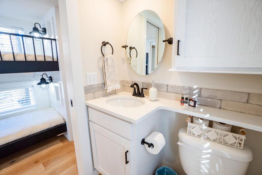 a bathroom with a toilet and a sink and a mirror at Tiny home Fire Pit Fishing Pond BBQ Sage Cabin in Gatlinburg