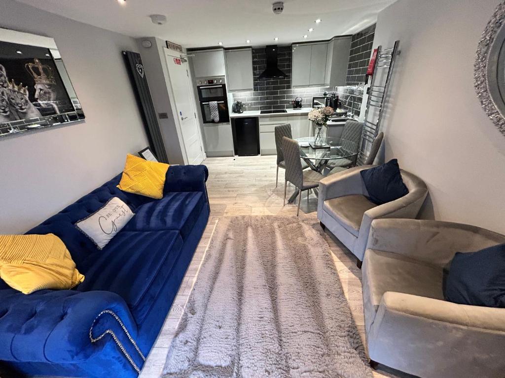 a living room with blue couches and a kitchen at The Penthouse - Luxury 2 Bed Apartment in Skegness in Skegness