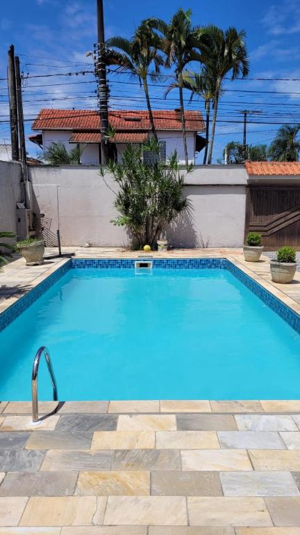 a large blue swimming pool in a yard at Casa Pazim in Itanhaém
