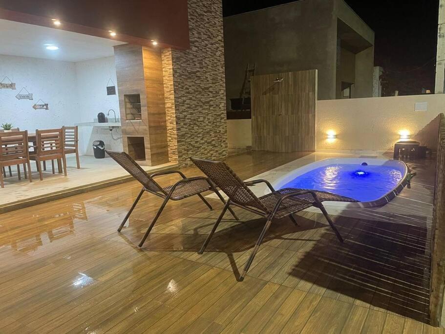 a couple of chairs and a pool in a room at Lar do Patacho in Pôrto de Pedras