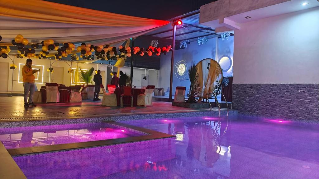 a room with a swimming pool and a table with people in it at The White House Farms in New Delhi