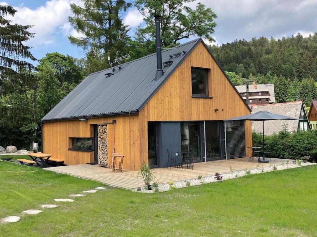 a large wooden barn with a deck in a yard at Villa in Bohemia with barbecue in Bedřichov