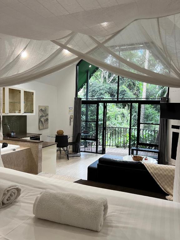 a bedroom with a bed and a kitchen with a large window at Gallery Walk Chalets - Tamborine Mountain in Mount Tamborine