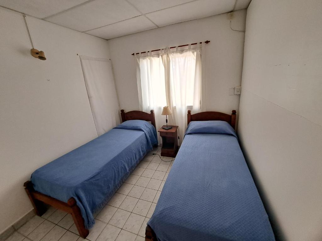 zwei Betten in einem Zimmer mit Fenster in der Unterkunft Casa España in San Antonio Oeste